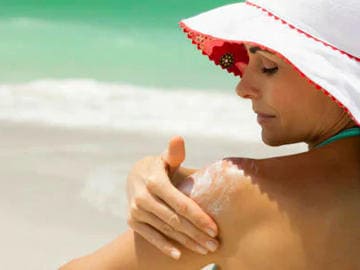 Femme en train de se passer de la crème pour éviter un coup de soleil