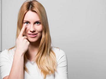 Frau trägt Kontaktlinsen, die bei ihr trockene Augen verursacht haben